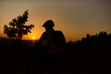 A cyclist riding a bike on a mountain at sunset