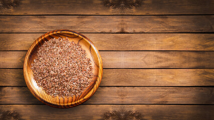 Organic flax seeds in the wooden bowl - Linum usitatissimum