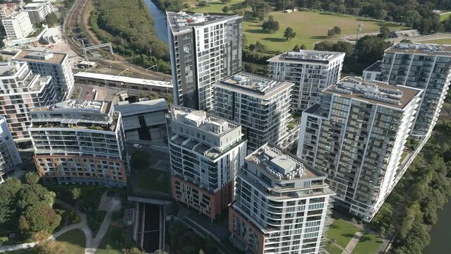Residential apartment complexes or units buildings with train lines in the background orbiting aerial view on sunny day