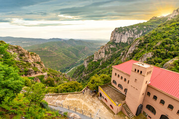 The mountains, monastery and cable car under an overcast sky at sunset at Montserrat in the...