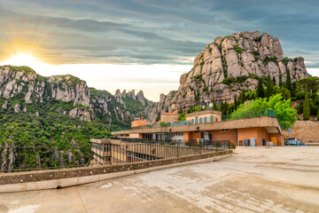 The mountains, monastery and cable car under an overcast sky at sunset at Montserrat in the...