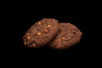 two chocolate cookies lie on a black background