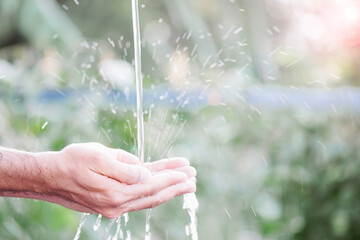 Water pouring and splash in man hand on nature background