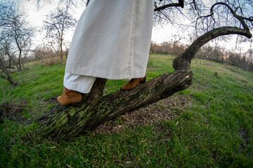 girl with long curly hair in a white raincoat near a tree in the park