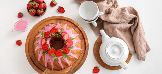 Tasty strawberry cake with teapot and cups on white background, top view