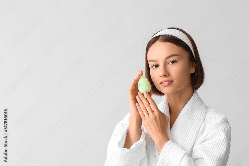 Sticker Pretty young woman with green makeup sponge on grey background