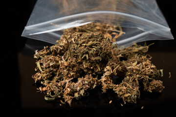 A close-up of marijuana buds in plastics zipper bag on black background.