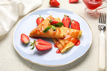 Plate of thin pancakes with strawberries and jam on white background