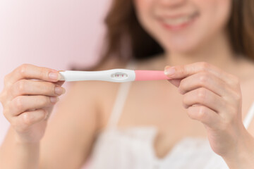 happy pregnant woman holding and showing positive pregnancy test