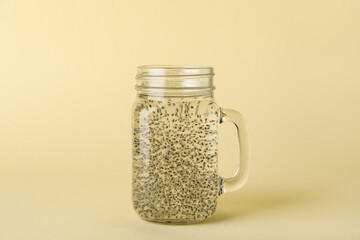 Mason jar of water with chia seeds on color background