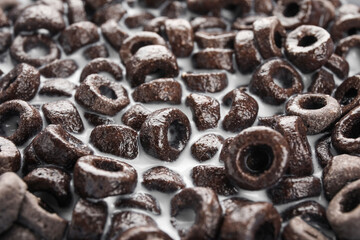 Delicious cereal rings with milk as background, closeup