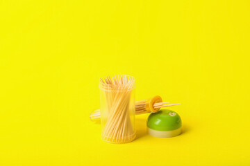 Holder with toothpicks on yellow background