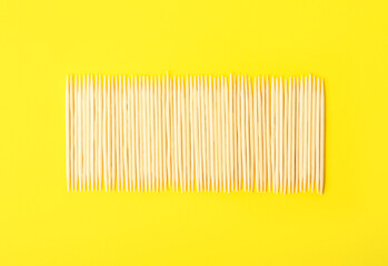 Row of wooden toothpicks on yellow background