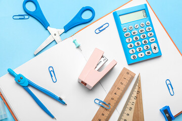 Stapler with different stationery supplies on blue background