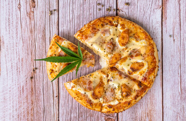 Homemade pizza with marijuana or cannabis leaves on wooden background. Fresh medical marijuana, cannabis decorate on pizza...