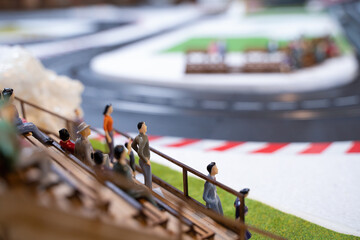Miniature doll in race track, Miniature people watching racing cars in the field. Selective focus