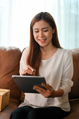 Fototapeta premium Female small online shop owner using tablet touchpad, checking sales and expenses.