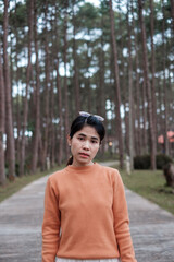 Fototapeta premium Happy woman in sweater traveling in pine tree forest, tourist visit at Doi Bo Luang, Chiang Mai, Thailand, Landmark and popular for tourist attractions. Vacation and journey concept