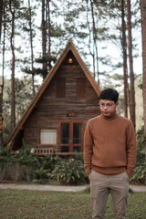 Happy man in sweater traveling in pine tree forest, tourist visit at Doi Bo Luang, Chiang Mai,...