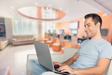 Portrait of smiling man using laptop. Adult male sitting on comfy couch in living room, watching video, taking break