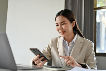 Successful asian businesswoman using smartphone to text with her business team.