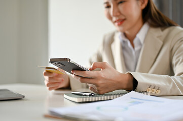cropped, Attractive Asian businesswoman holding a smartphone and a credit card.
