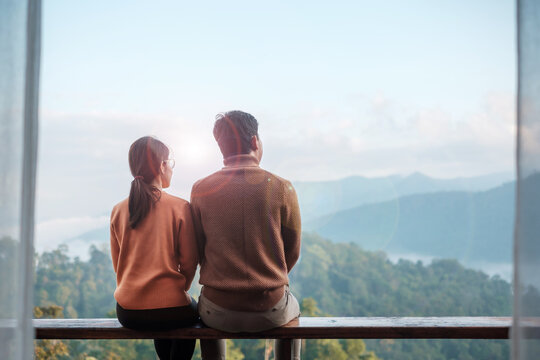 Couple tourist relaxing and looking mountain view at countryside home or homestay in the morning. Vacation, together travel, honeymoon, blogger, journey, trip and relaxing concept