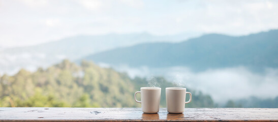 couple White mug of hot coffee or tea on wooden table in the morning with mountain and nature...