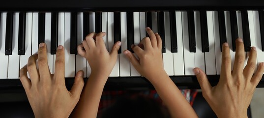 Family Unity Concept Image - Top view of piano player and child and father hands playing music.