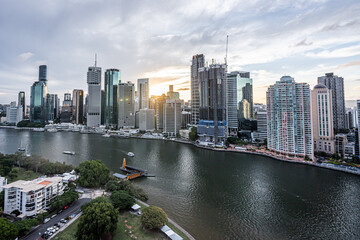 Brisbane city skyline viewed from the top of Story Bridge at sunset with glowing river and urban skyscrapers