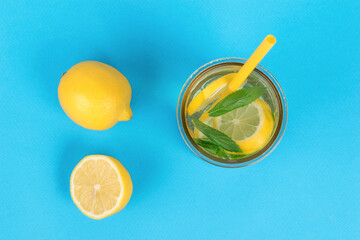 Fresh lemons and a glass of refreshing lemonade on a blue background.