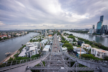 Brisbane city skyline viewed from the top of Story Bridge at sunset with glowing river and urban skyscrapers