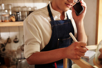 Cropped image of barista discussing details of order with customer on phone