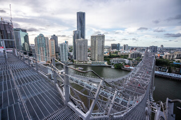 Modern city skyline and river seen from steel truss bridge walkway