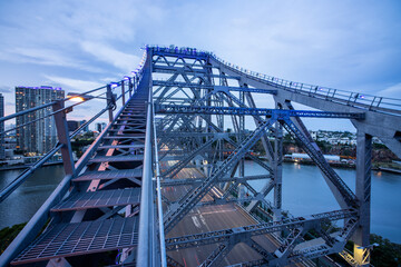 Blue steel truss bridge spanning river under partly cloudy sky
