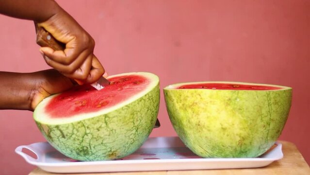 person holding a slice of melon. Person slicing watermelon into pieces. 