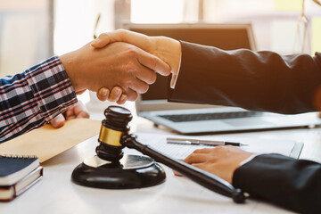 Close up of woman lawyer hand and man client shaking hand collaborate on working agreements with contract documents at the office.