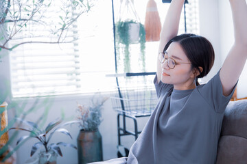 明るい室内でストレッチ体操をするワンピース姿の日本人女性