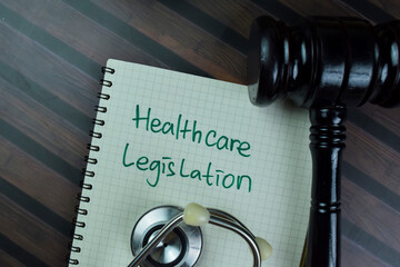 Concept of Healthcare Legistation write on a book with gavel isolated on Wooden Table.