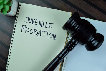 Concept of Juvenile Probation write on a book with gavel isolated on Wooden Table.