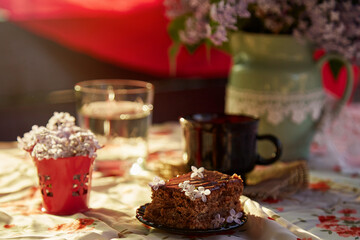 Fototapeta na wymiar Homemade chocolate cake brownie. Dessert and cup of coffee among flowers. Atmospheric breakfast.