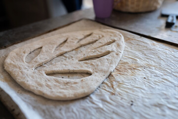 A baker shapes and cuts traditional French Fougasse bread. Front view.