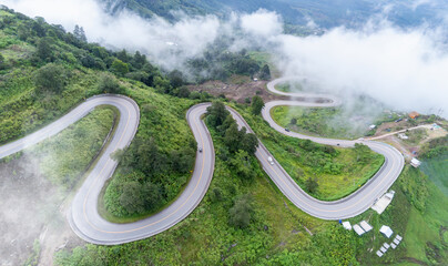 Aerial top view drone photo over green mountains with white fog floating and  paths exciting steep...