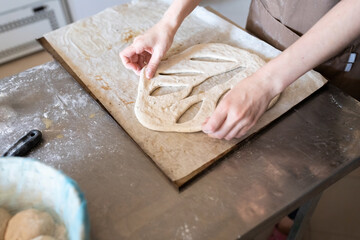 A baker shapes and cuts traditional French Fougasse bread. Front view.