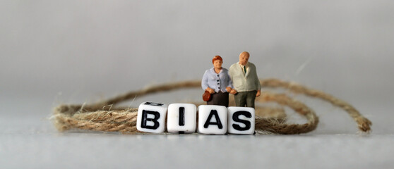 Business concept with white cube arranged in the word  ’BIAS' and miniature people. The concept of prejudice against the elderly and the infirm.
 - obrazy, fototapety, plakaty