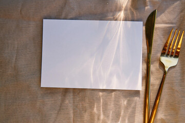 Aesthetic minimalist stationery card mock up with hard shadows, sunlight and cutlery. Top view, copy space. Menu design, postcard, invitation mockup.