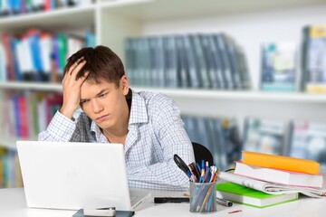 Stressed Male University Or College Student With Poor Mental Health Studying With Laptop In Room