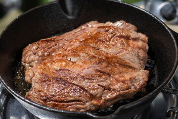 アウトドアのキャンプ場でスキレットを使ってステーキ肉を焼く