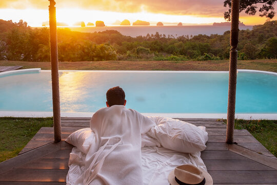 Happy Man Traveler Enjoy Beautiful Ocean View, Tourist Relaxing In Tropical Luxury Resort With Swimming Pool. Leisure, Travel And Summer Vacation Concept