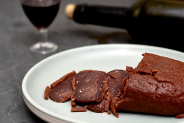 sliced basturma on a plate next to a bottle of wine and a glass